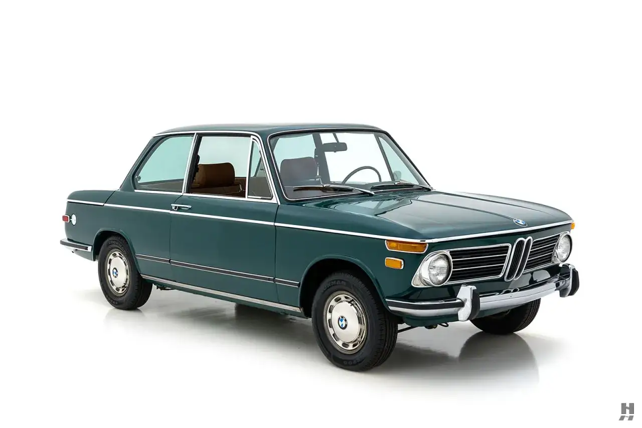 Klasyczny, zielony BMW 2002 z brązowym wnętrzem, prezentowany na białym tle.