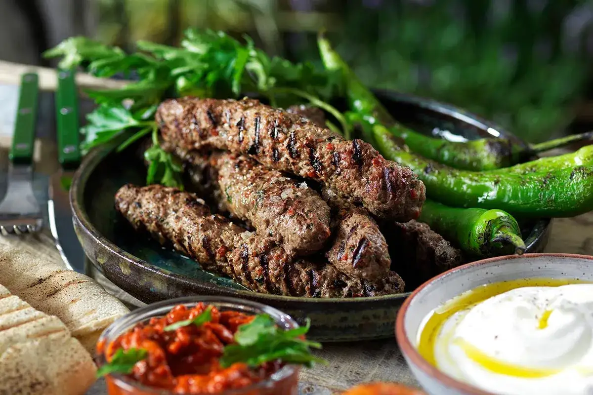 Grillade cevapcici med gröna chili, persilja, pitabröd och en röra. Ett perfekt cevapcici recept för sommaren.