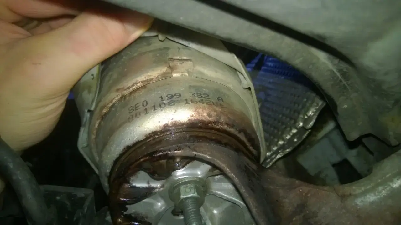 Wyciek oleju z mocowania silnika p1577 audi. Widoczna ręka mechanika i numer części.