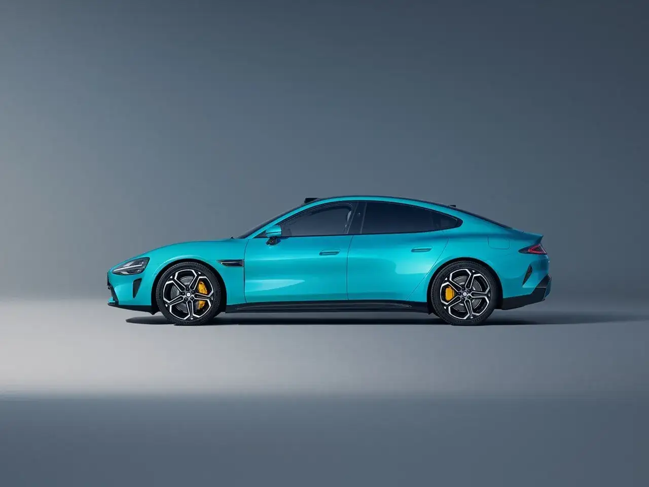 Eleganckie, turkusowe auto Xiaomi w profilu, z żółtymi zaciskami hamulcowymi i nowoczesnymi felgami.