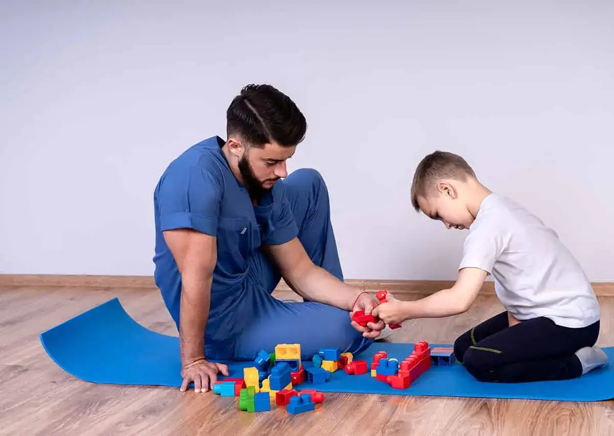 Un terapeuta y un niño juegan con bloques de construcción, parte de la terapia ocupacional para niños.
