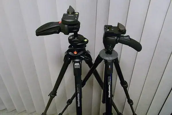 aparat fotograficzny obok statywu z widoczną głowicą i szybkozłączką