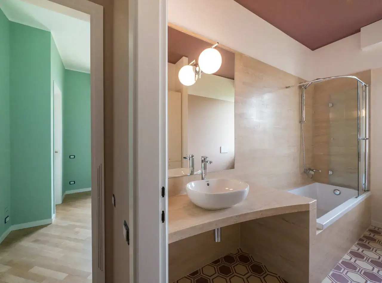 Bagno anni 70 con vasca, lavabo moderno e pareti verdi. Un tocco retr&ograve; con un design contemporaneo.