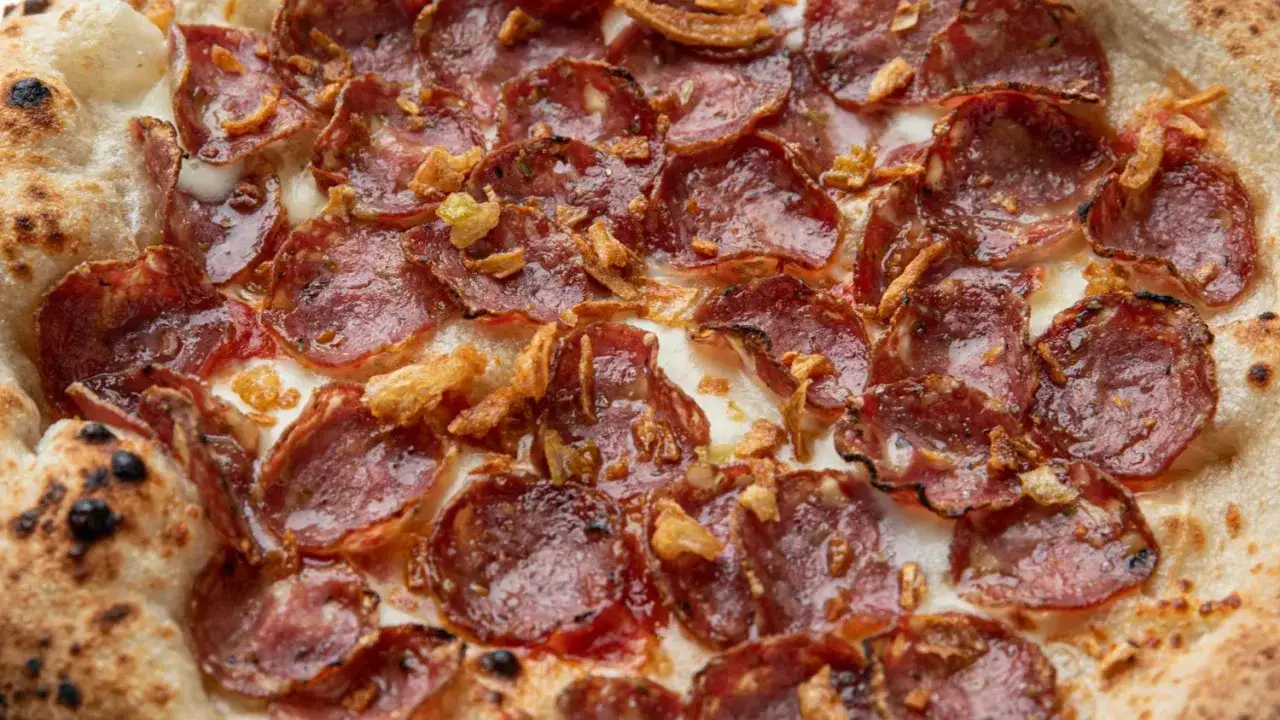 Pizza z chrupiącym ciastem, obficie pokryta plastrami pikantnego **peperoni**, roztopionym serem i chrupiącą cebulką.