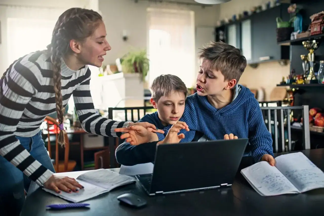 Tres ni&ntilde;os intentan estudiar, pero los problemas de concentraci&oacute;n se hacen evidentes. Uno se&ntilde;ala la pantalla, otro mira con frustraci&oacute;n, y la mayor intenta ayudar.