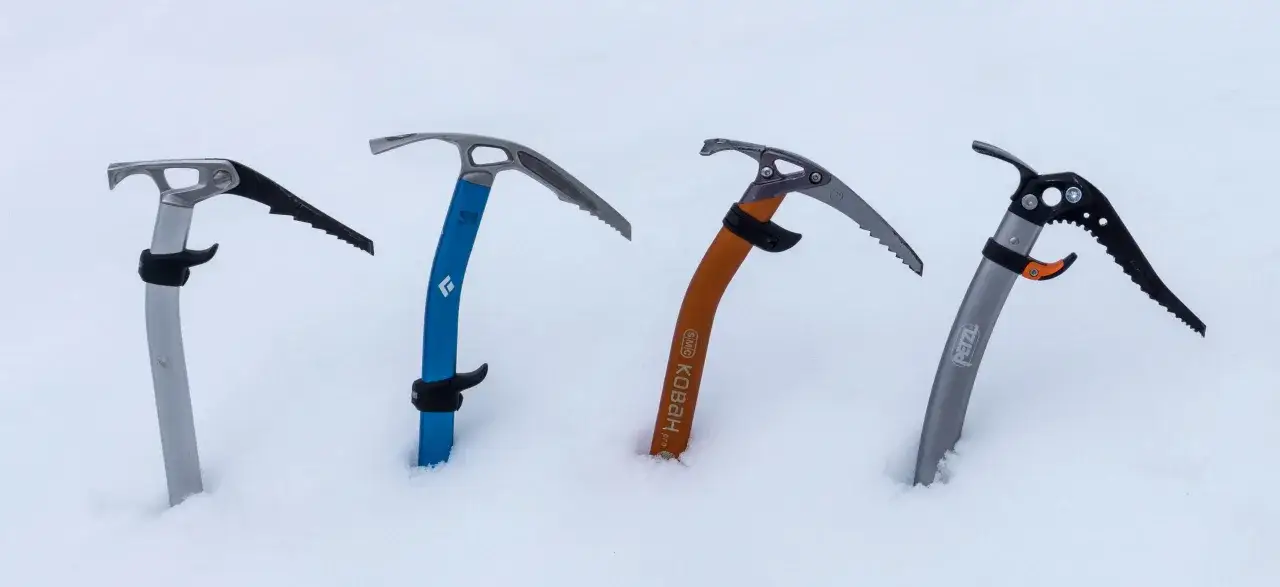 Quatre piolets de montagne, prêts pour l'aventure, plantés dans la neige.
