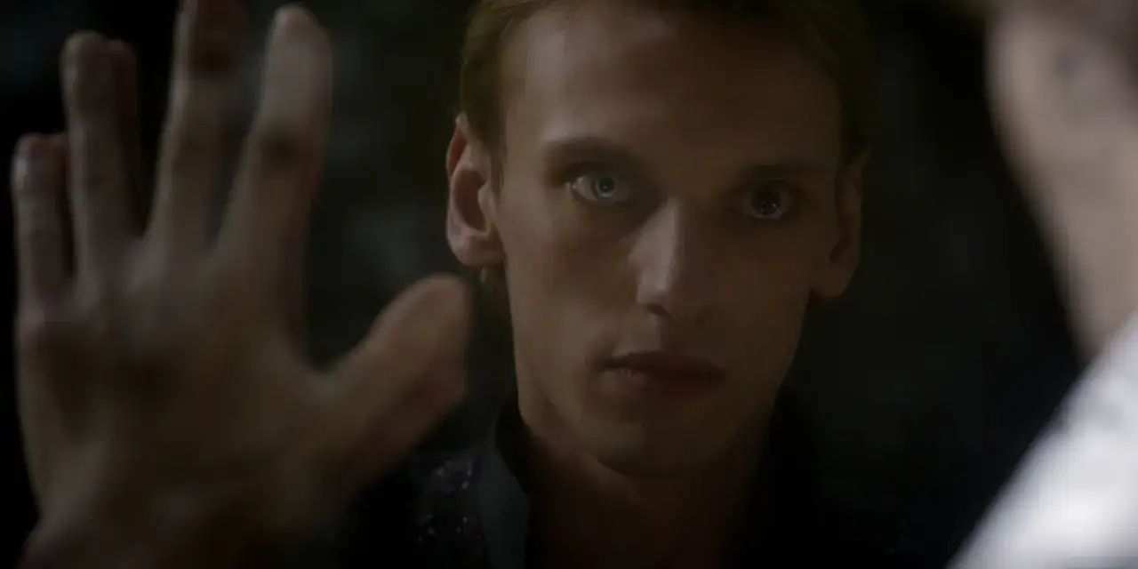 Jamie Campbell Bower jako Gellert Grindelwald, z jednym okiem białym, patrzy na widza.