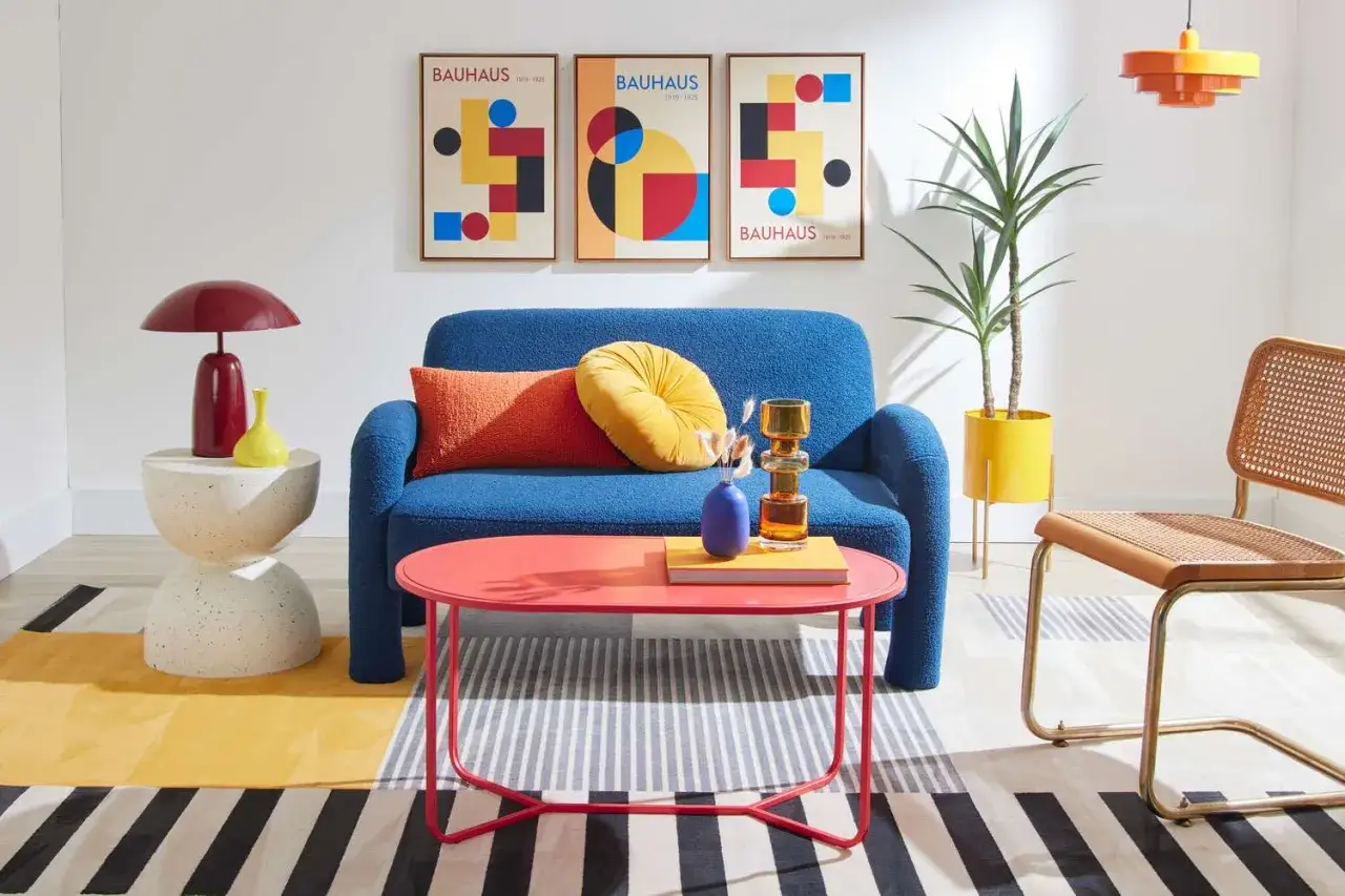 Salon w stylu bauhaus: niebieska kanapa, kolorowe plakaty, geometryczne kształty i odważne akcenty.
