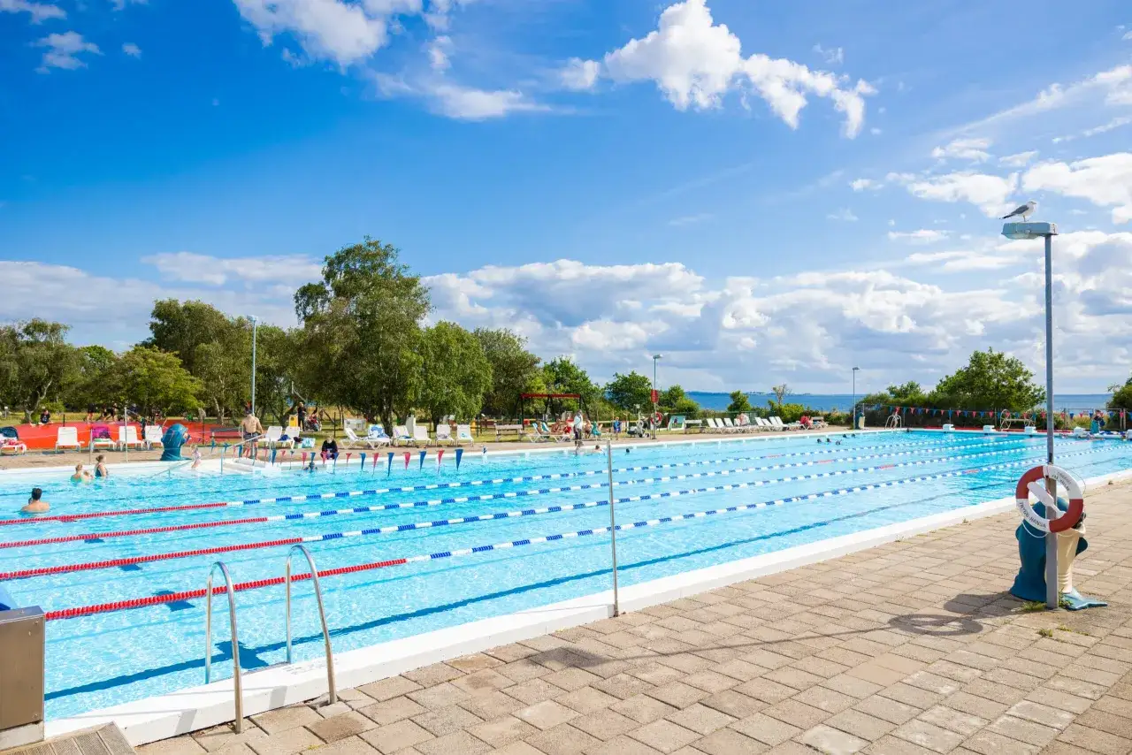 Stor utomhuspool med simbanor, solande g&auml;ster och gr&ouml;nska runtom. Perfekt f&ouml;r en sommardag, som recensionerna f&ouml;r first camp r&aring;&aring; vallar-helsingborg vittnar om.