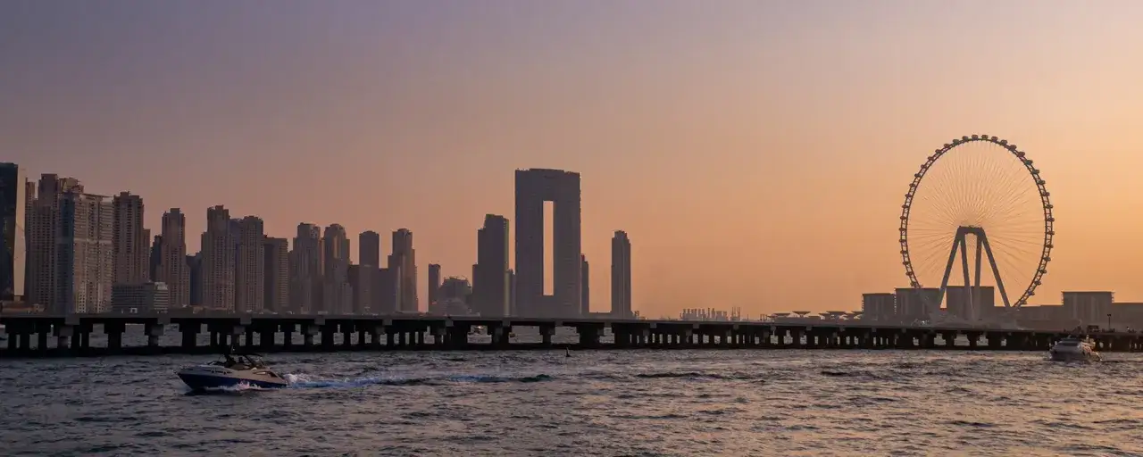 Zachód słońca nad Dubajem. Widok na nowoczesne wieżowce, diabelski młyn i most. Idealne miejsce, by zobaczyć, co Dubaj ma do zaoferowania.