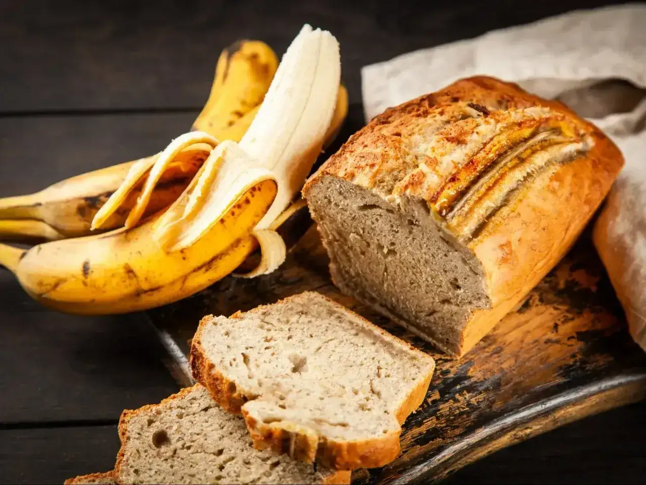 Pyszny chlebek bananowy, obok świeżych bananów, kusi apetycznym wyglądem. Idealny na śniadanie lub deser.