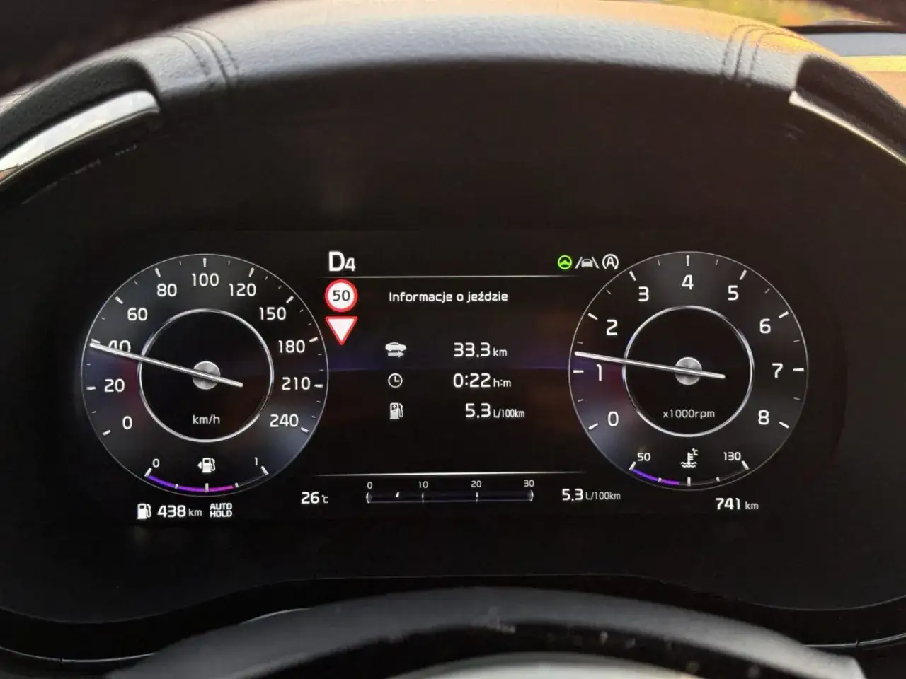 Cyfrowy kokpit pokazuje prędkość 40 km/h, zużycie paliwa 5.3 L/100km i aktywny asystent pasa ruchu.