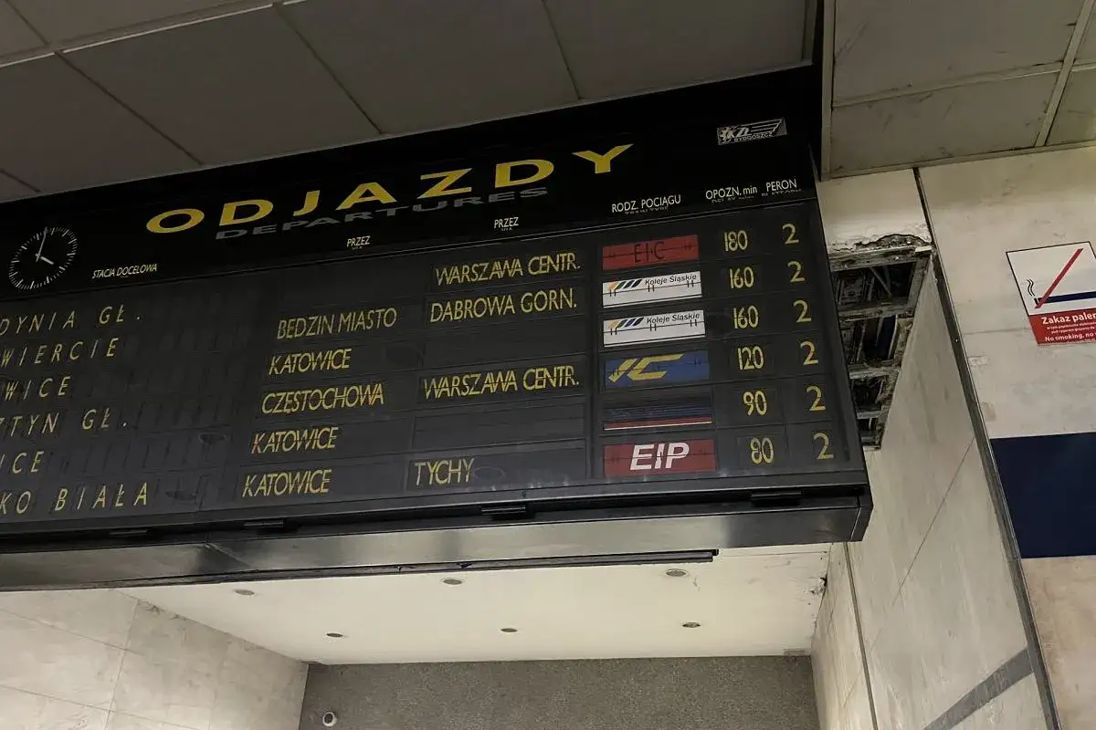Tablica odjazdów PKP z informacjami o trasach, np. do Warszawy, Katowic i Tychów.