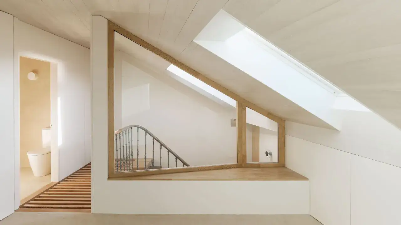 Interno luminoso con scala a vista, bagno discreto e un angolo lettura. Stile minimal casa con legno e bianco.