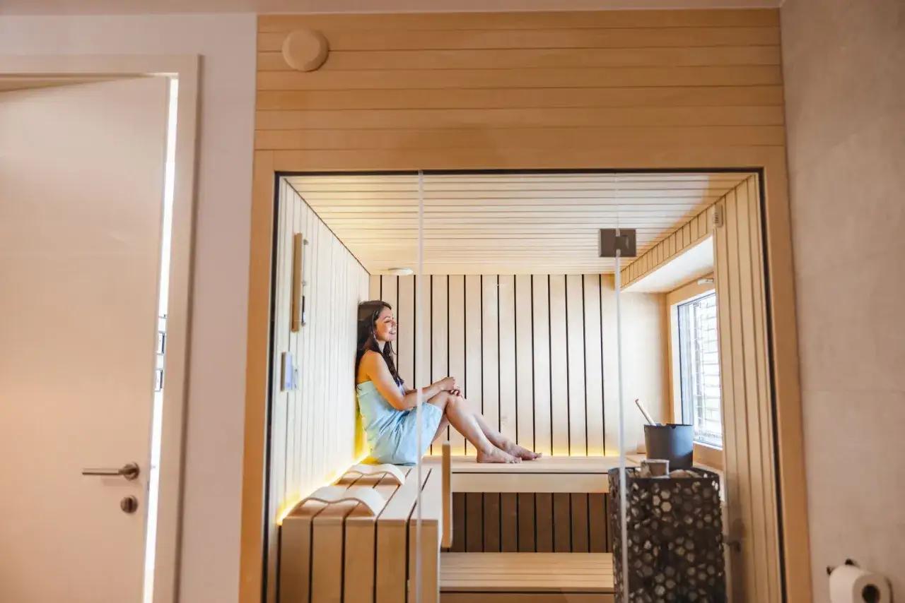 Femme d&eacute;tendue dans un sauna en bois. Elle se demande combien de sauna par semaine est id&eacute;al pour le bien-&ecirc;tre.