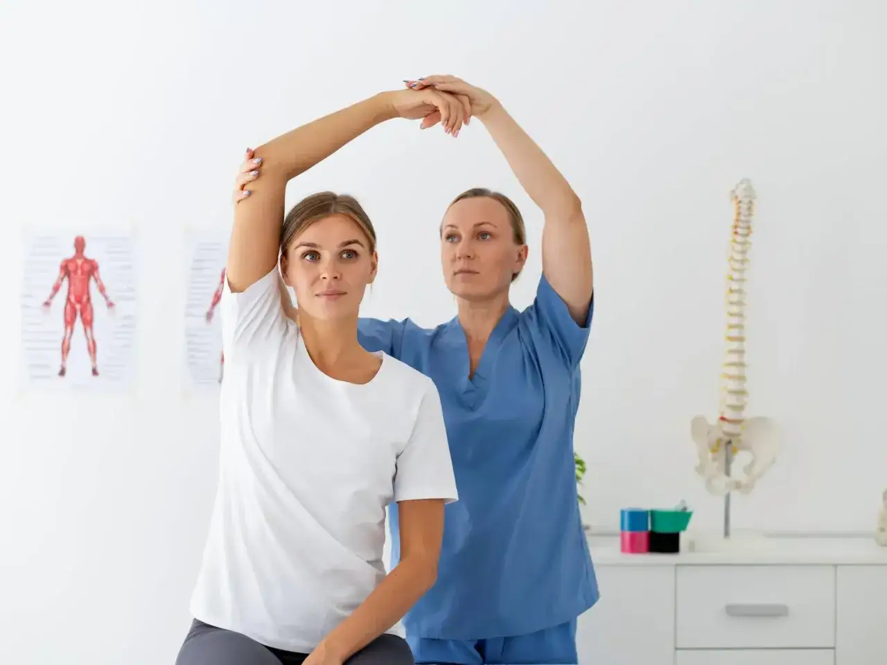 Physiotherapeutin hilft Patientin bei der Armbewegung. Dies ist ein Beispiel dafür, was Krankengymnastik ist: Rehabilitation und Bewegungstherapie.