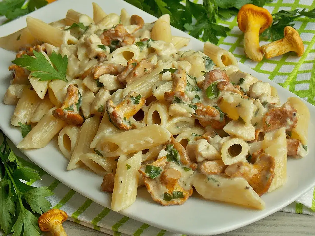 Penne z kurkami w kremowym sosie, ozdobione natką pietruszki. Pyszny makaron w sosie kurkowym, idealny na obiad.