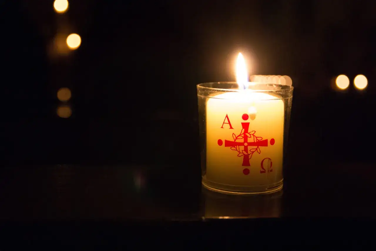 Brennende Kerze mit christlichen Symbolen (Alpha, Omega, Kreuz) erinnert an die osterfeuer christliche bedeutung.