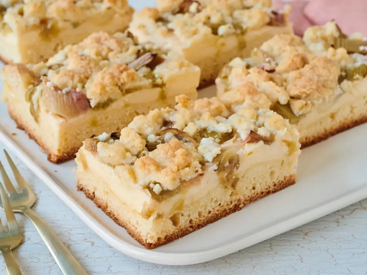 Saftiger Rhabarberkuchen mit Pudding vom Blech, bestreut mit knusprigen Streuseln. Ein Genuss für jeden Kaffeetisch.
