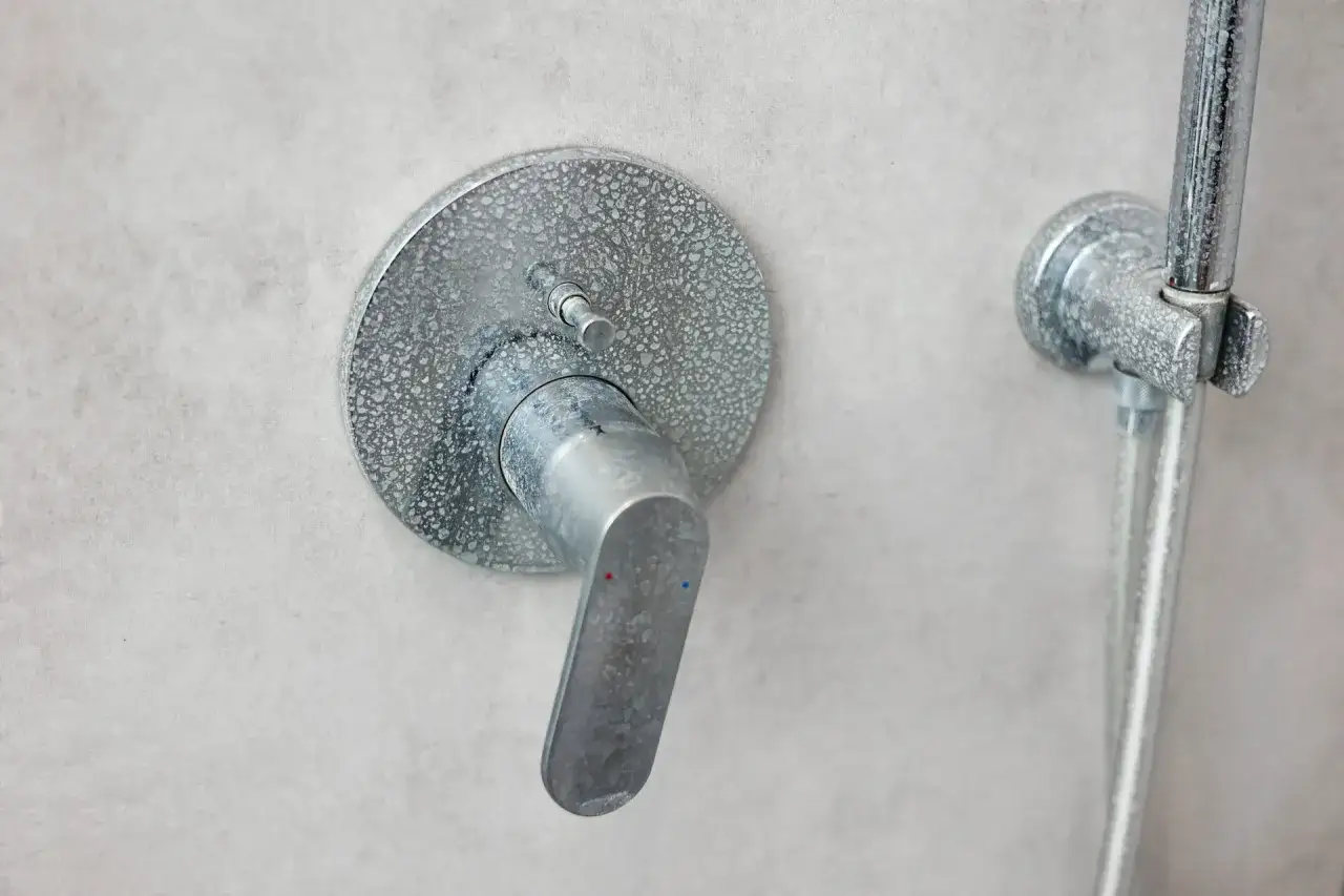 Robinet de douche entartré, montrant la nécessité de nettoyer le calcaire de la douche pour un aspect neuf.