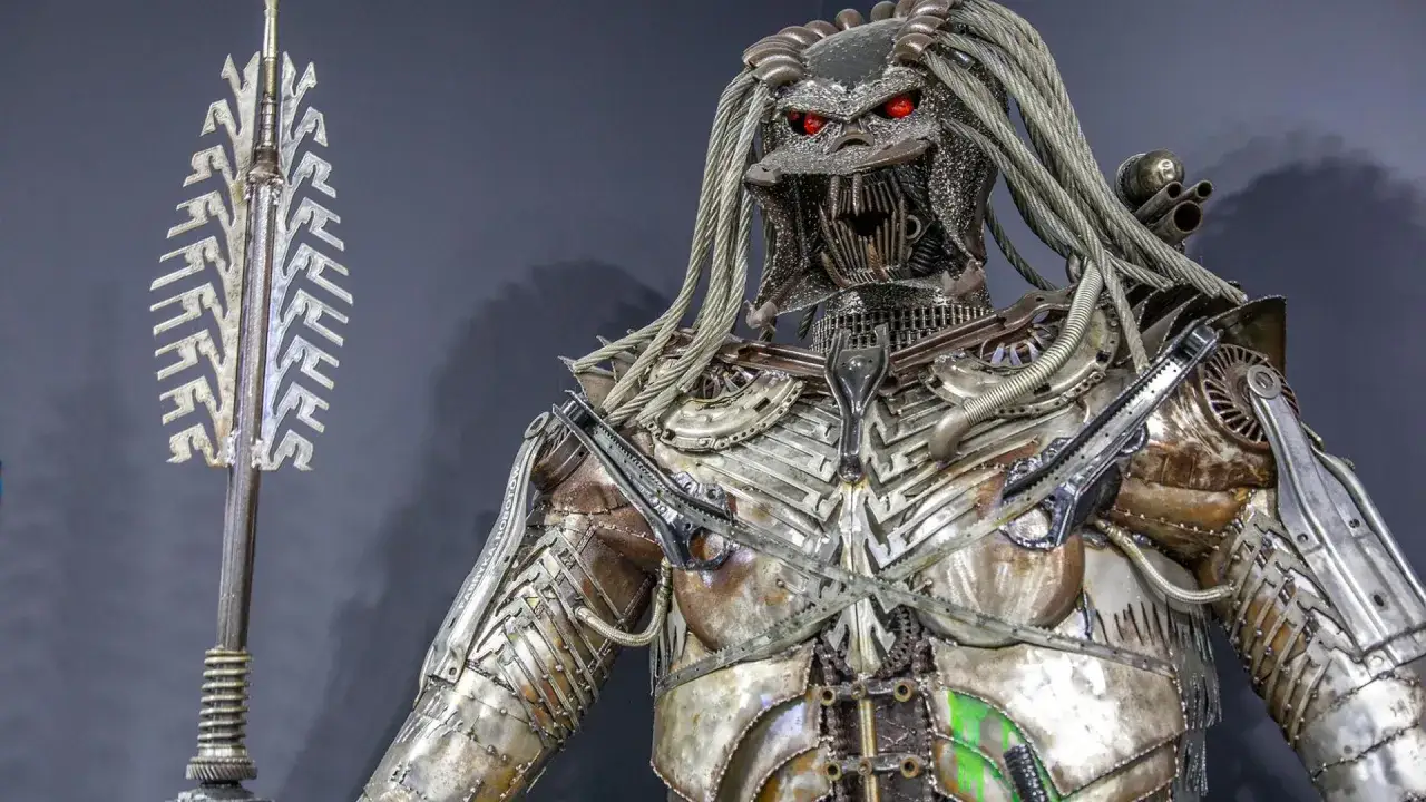Metalowy Predator z czerwonymi oczami, zrobiony z części samochodowych, czeka na zwiedzających w Muzeum Robotów Moszna.