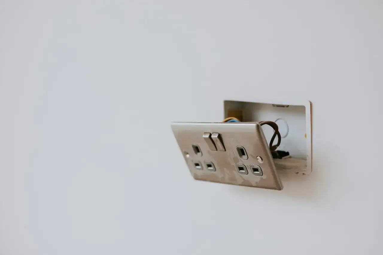 Odkryta puszka z przewodami i gniazdko elektryczne, widoczny brak zera w gniazdku.