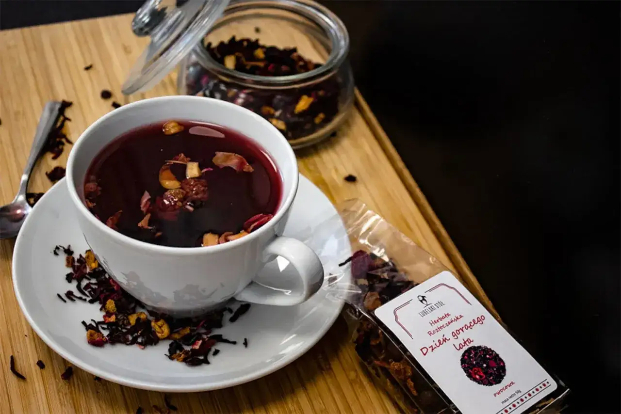 Aromatyczna herbata malinowa w filiżance, obok słoik z suszem i paczka z napisem