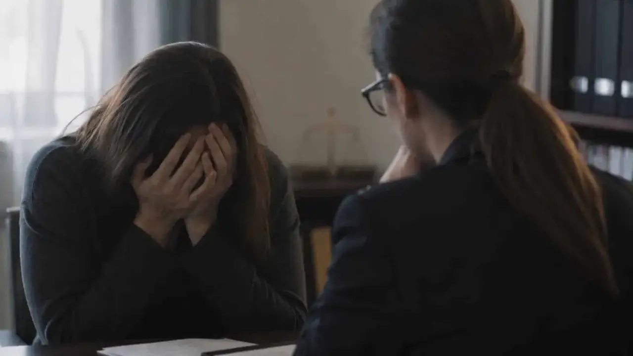 Kobieta w rozpaczy, ukrywająca twarz w dłoniach, opowiada o gwałcie prawniczce.