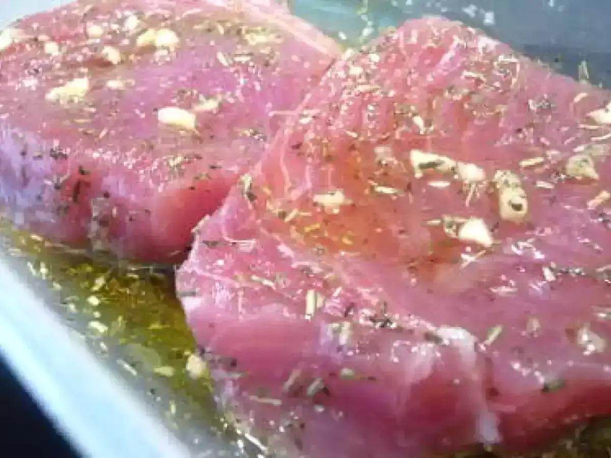 Deux beaux steaks de thon rouge marin&eacute;s dans de l'huile d'olive, de l'ail et des herbes. Parfait pour une recette facile et savoureuse.