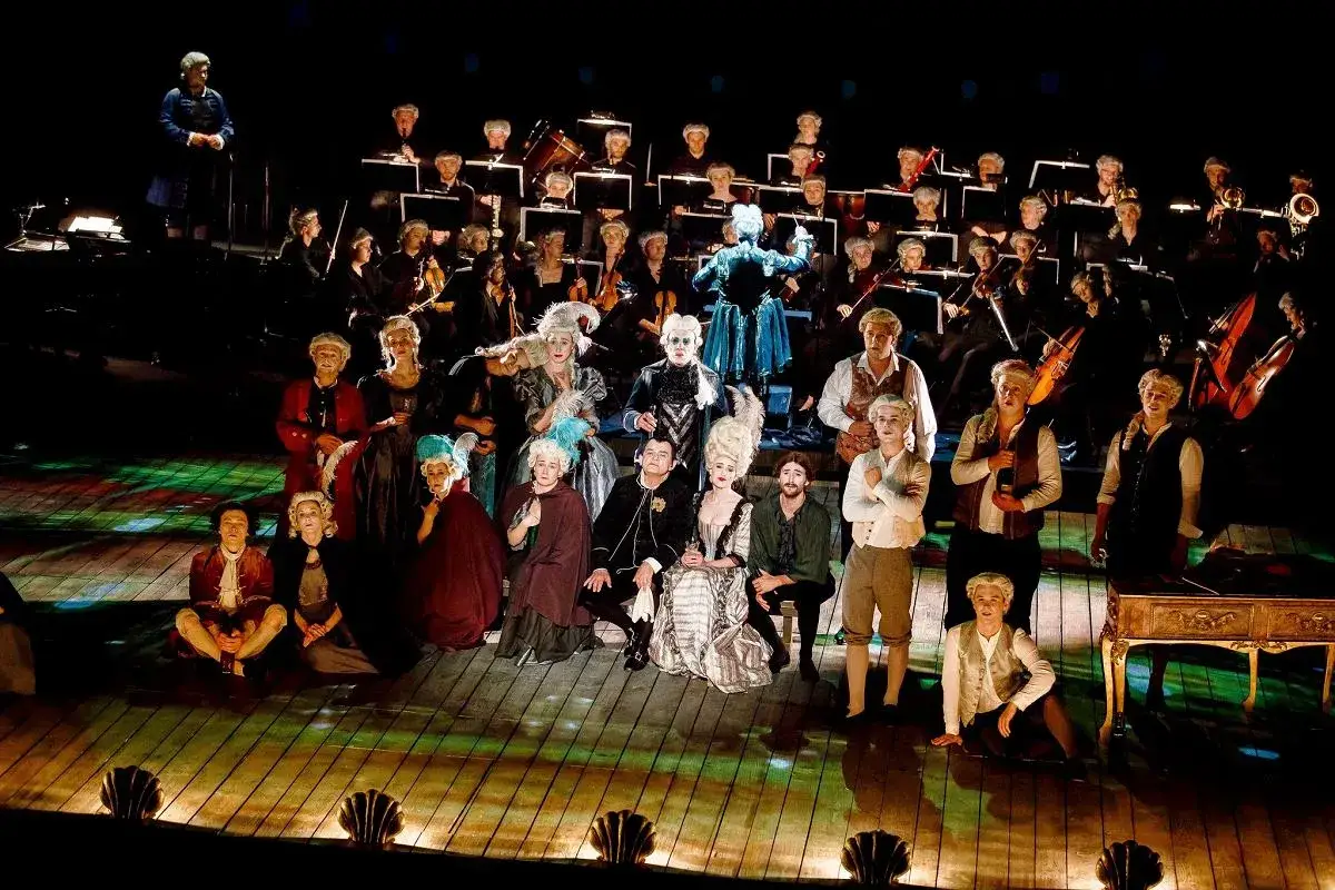 Aktorzy w strojach z epoki i orkiestra przygotowują się do spektaklu w teatrze w stolicy.