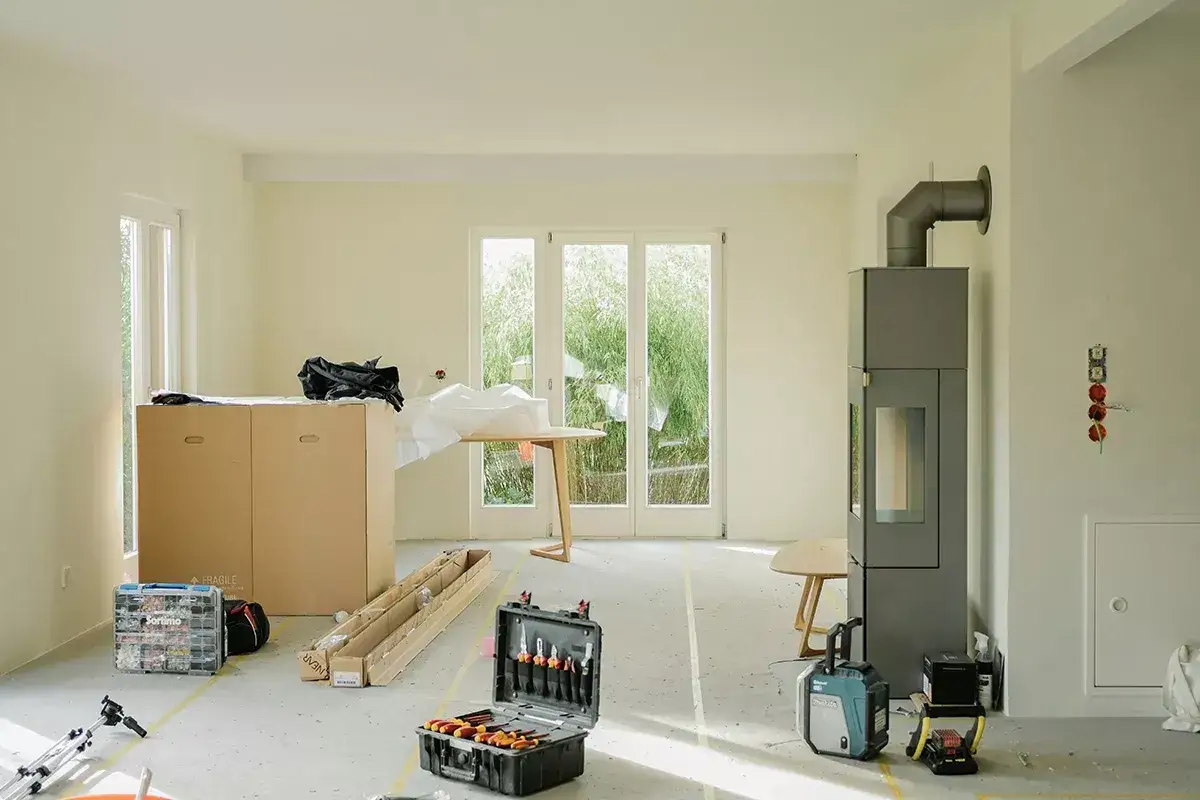 Ristrutturare casa con 10.000 euro è possibile! L'ambiente è in fase di allestimento, con scatole, attrezzi e un nuovo camino moderno.