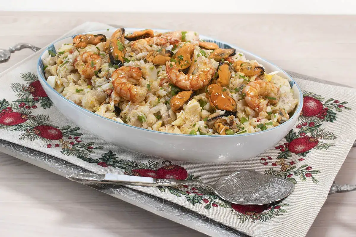Delicioso salpic&oacute;n de pescado con gambas y mejillones, servido en un cuenco blanco sobre un mantel festivo.
