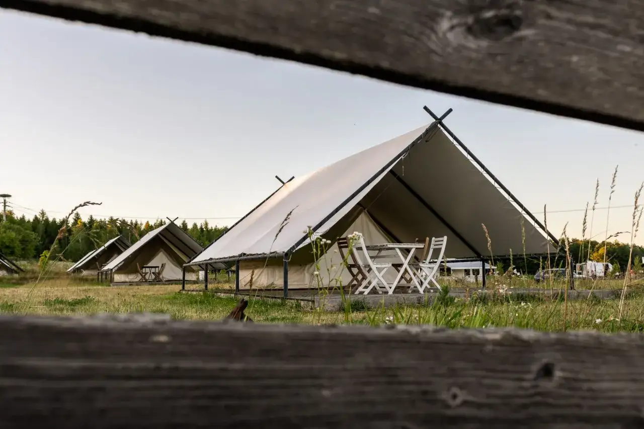 Namioty glampingowe na szelągówka camping. Drewniany stolik i krzesła przed jednym z namiotów.