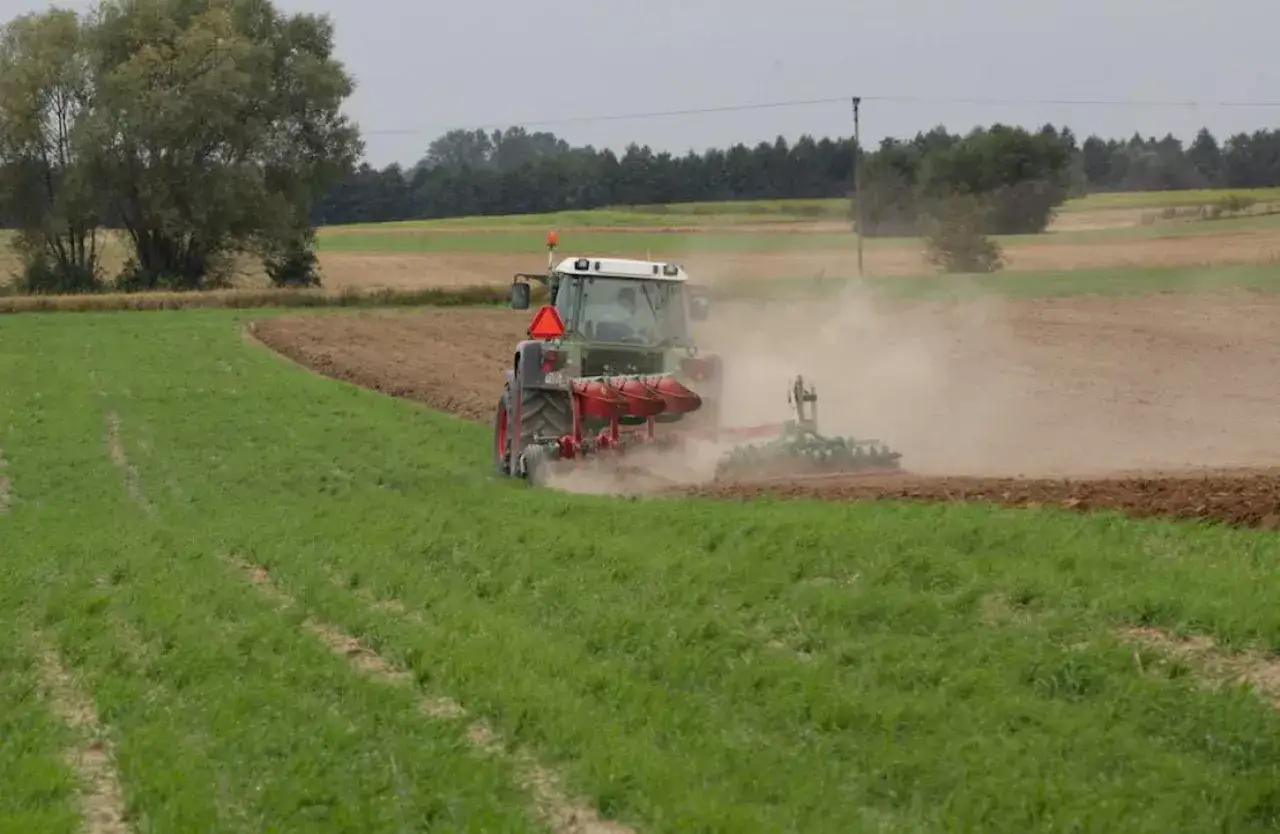 Traktor orze pole, wzbijając tumany kurzu. Czy rolnicy płacą podatek od nieruchomości za takie pola?