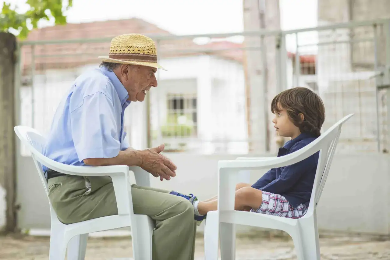 Abuelo con sombrero habla con su nieto, una escena com&uacute;n cuando los padres dejan a sus hijos con los abuelos.