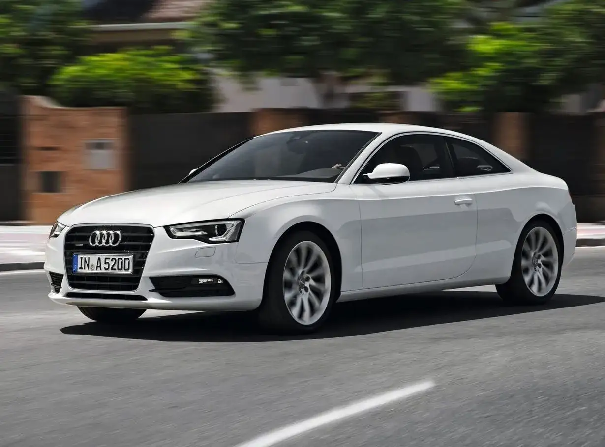 Białe Audi A5 w ruchu drogowym, podczas testu jazdy. Eleganckie coupe mknie po asfaltowej drodze, ukazując swoje sportowe linie.
