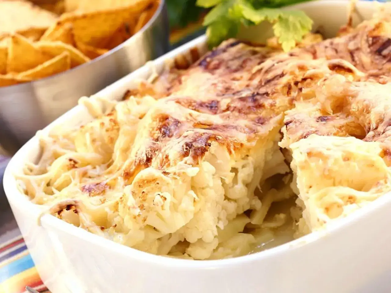 Herzhafte Blumenkohl-Gratin-Rezepte: Cremiger Blumenkohl mit geschmolzenem K&auml;se, serviert mit Tortilla-Chips.