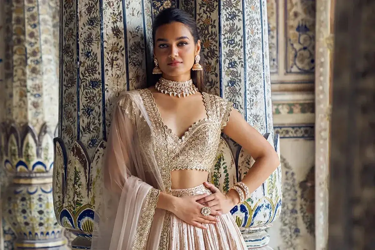 A woman models a shimmering gold lehenga, a stunning example of traditional clothing India, adorned with intricate embroidery and jewelry.