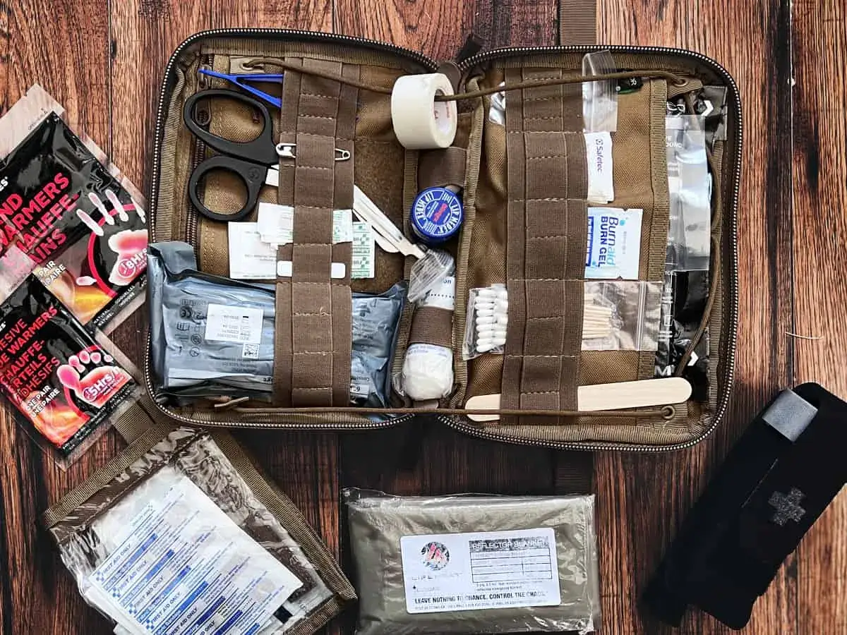 Kit de primeros auxilios abierto con tijeras, gasas, vendas, calentadores y otros elementos esenciales para consejos de supervivencia.