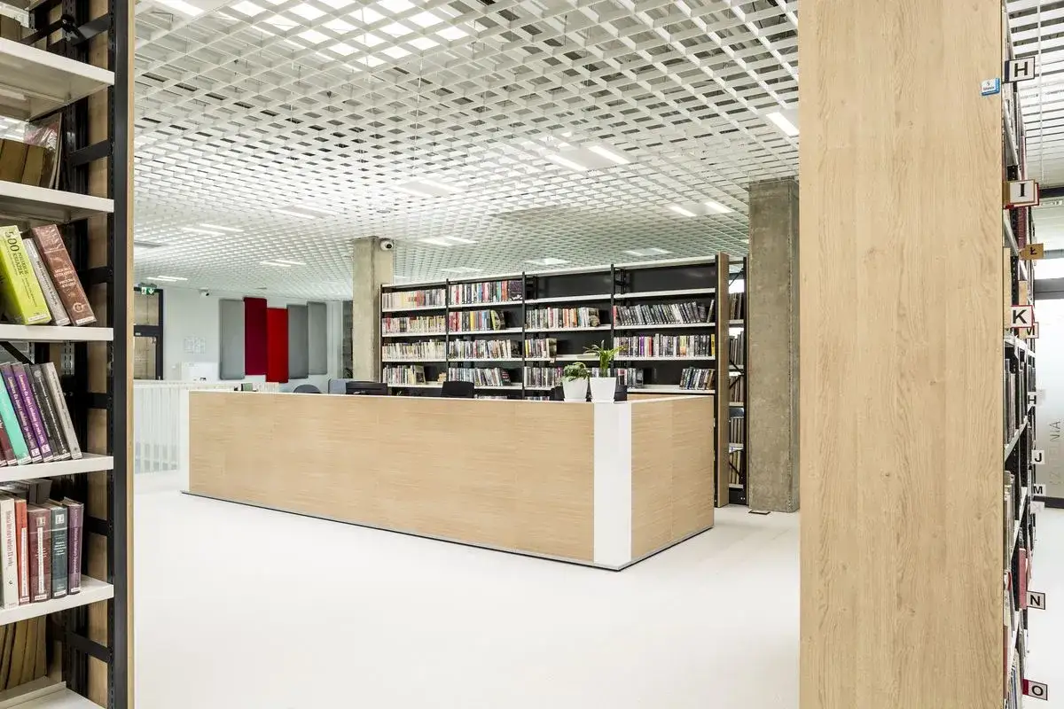 Nowoczesna biblioteka miejska w Pradze z regałami pełnymi książek i jasnym, przestronnym wnętrzem.