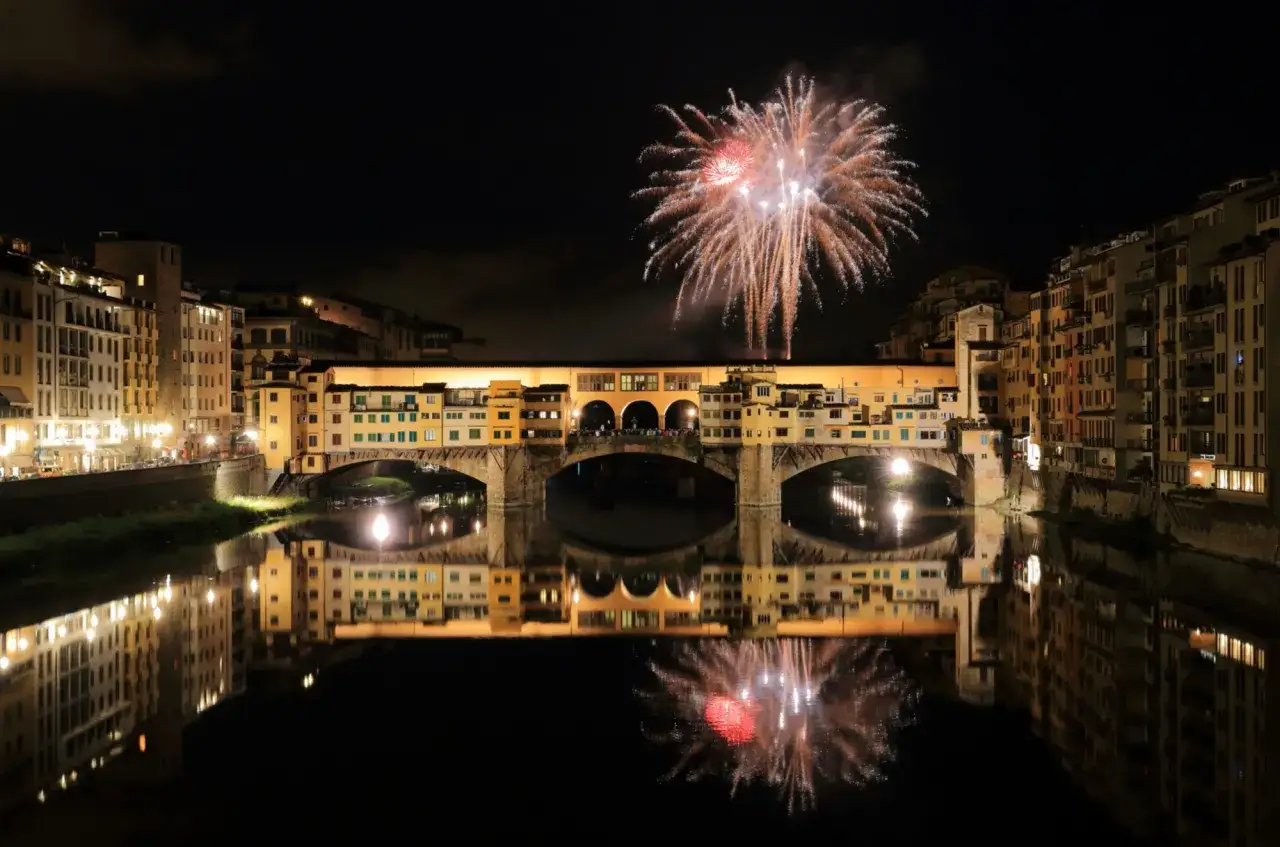 Feux d'artifice illuminant le Ponte Vecchio &agrave; Florence, une date m&eacute;morable pour une f&ecirc;te inoubliable. Reflets dans l'Arno.
