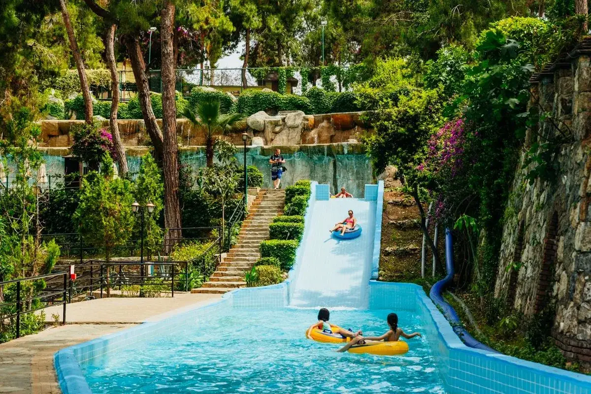 Wodne szaleństwo w hotelu Utopia w Turcji. Dzieci i dorośli zjeżdżają na pontonach po śliskiej zjeżdżalni prosto do basenu.