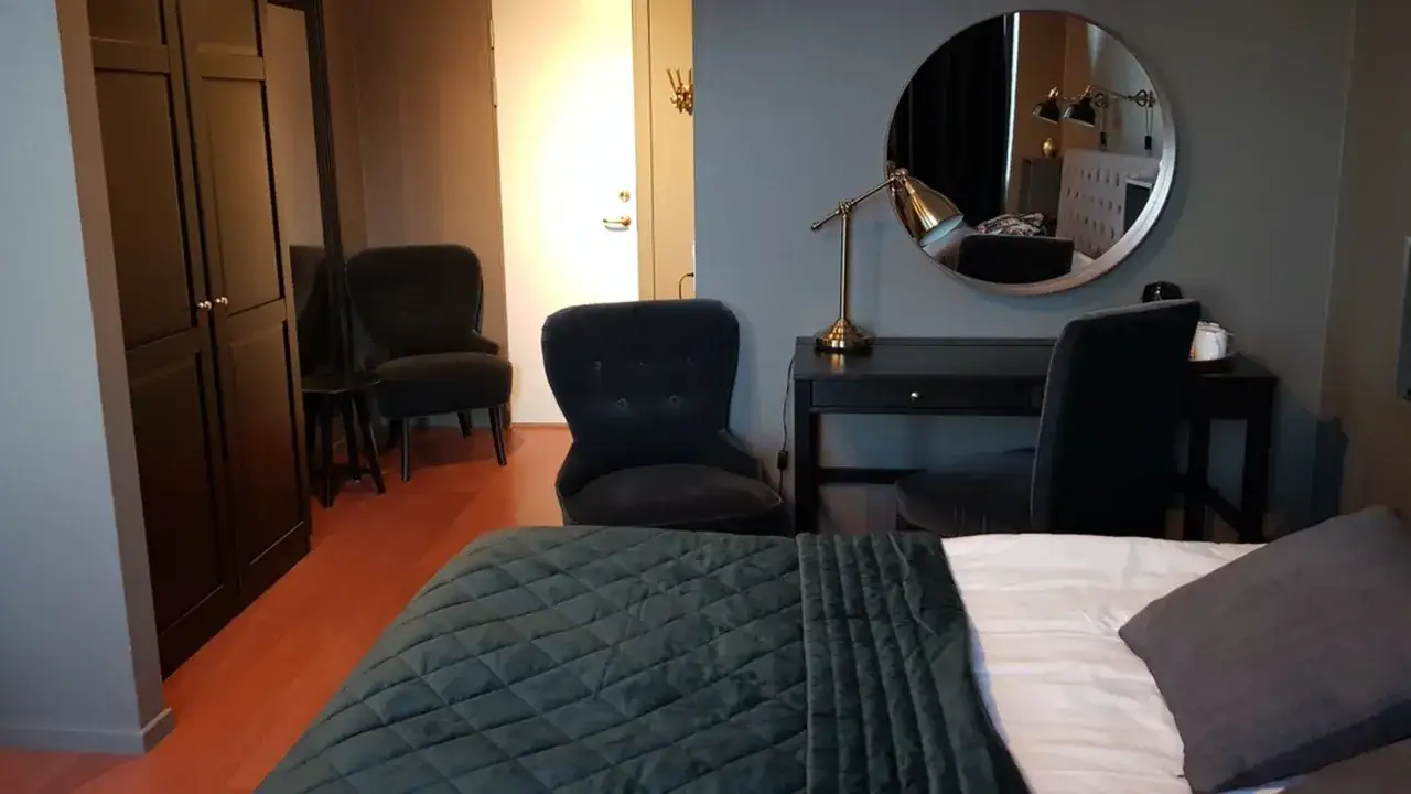 Ett modernt rum p&aring; Haparanda Stadshotell med en bekv&auml;m s&auml;ng, skrivbord och f&aring;t&ouml;ljer.