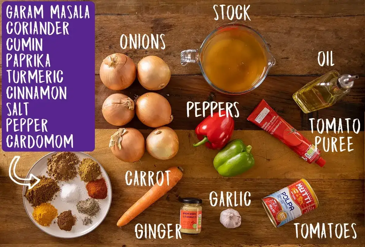 Zutaten für ein leckeres Curry selber machen: Zwiebeln, Paprika, Karotte, Ingwer, Knoblauch, Tomaten, Gewürze, Brühe, Öl und Tomatenpüree.