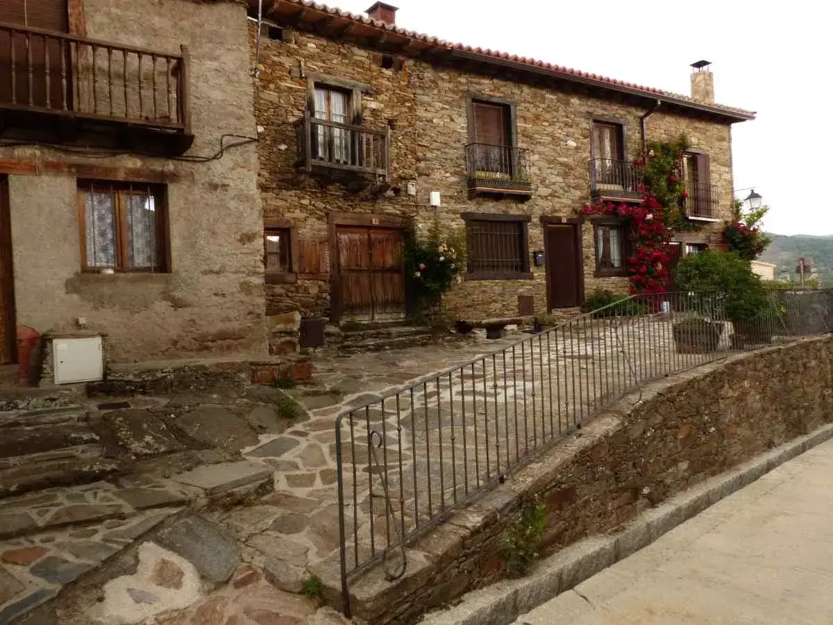 Casas de piedra con balcones de madera y flores rojas, un rinc&oacute;n encantador de los lugares secretos de la sierra de Madrid.