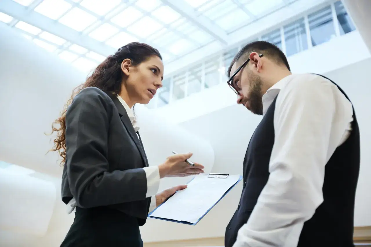 A woman points at a document, discussing a potential nonprofit board member conflict of interest with a man.
