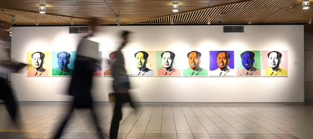 A gallery wall displays Andy Warhol's Mao portraits in vibrant colors. This is why rich people buy art: for status, investment, and conversation starters.