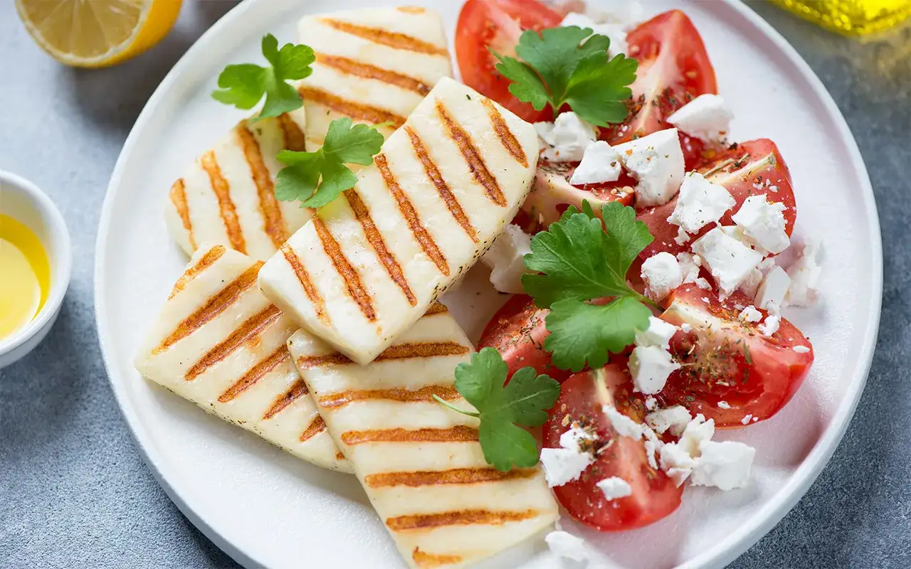 Grillad marinerad halloumi serveras med tomater, fetaost och färska örter. En härlig och fräsch rätt!