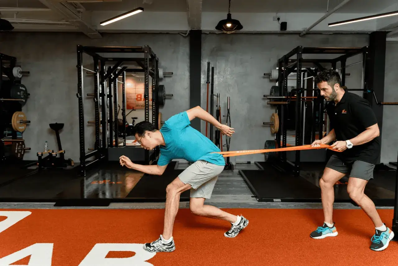 Trener medyczny pomaga sportowcowi w ćwiczeniu oporowym z gumą.