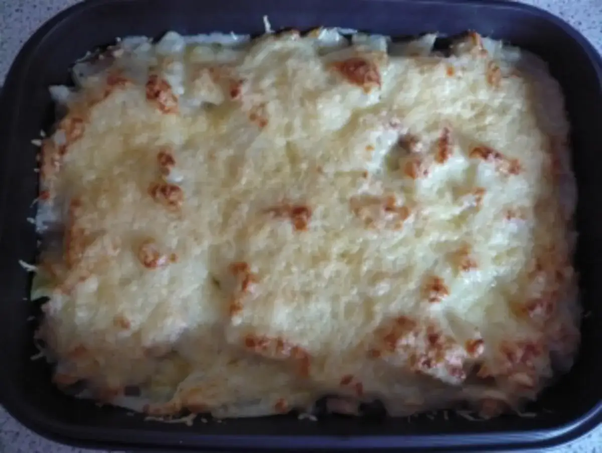 Ein goldbraun überbackener Kohlrabi-Auflauf in einer Auflaufform, mit geschmolzenem Käse und leicht gebräunten Stellen.